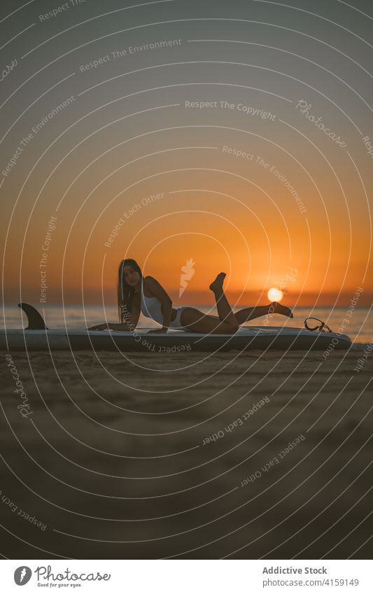 Schlanke Frau auf Paddle Board am Strand Paddelbrett SUP Holzplatte Sand Sonnenuntergang Lügen sich[Akk] entspannen MEER Badeanzug passen schlank Sommer Küste