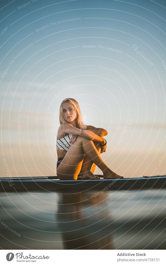 Sorglose Frau auf Paddleboard im Meer Paddelbrett MEER sich[Akk] entspannen Sonnenuntergang SUP Holzplatte Surfbrett schlank Badeanzug Sommer sitzen ruhen