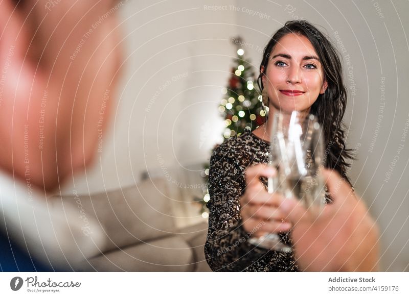 Lächelnde Frau stößt mit einem Freund auf einer Party an Klirren Glas Champagne Weihnachten feiern Feiertag trinken festlich Zusammensein stilvoll Alkohol