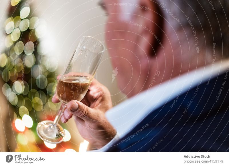 Eleganter Mann trinkt Champagner zu Weihnachten zu Hause Tisch elegant Feiertag reif feiern festlich männlich ernst Party fröhlich Alkohol Glas Outfit trinken