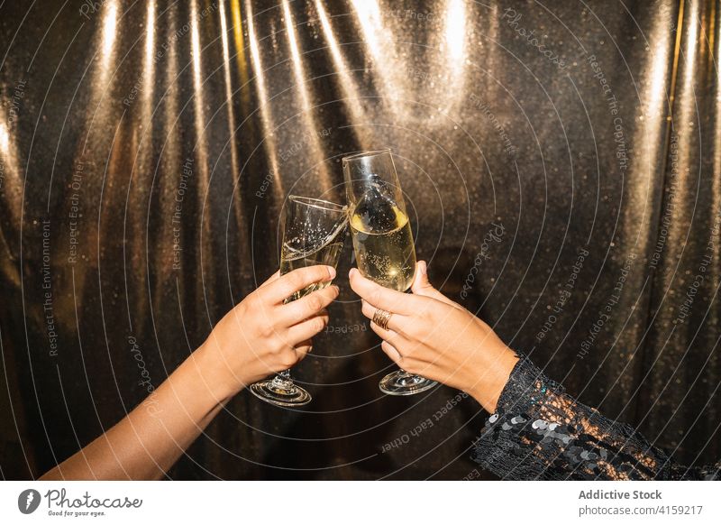 Crop-Frauen stoßen auf einer Party mit Gläsern an Klirren Glas Champagne feiern Zuprosten golden Alkohol Feiertag glänzend Freund trinken festlich Veranstaltung