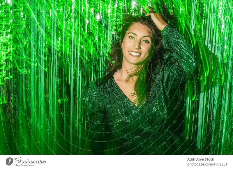Fröhliche Frau spielt mit grünem Lametta Party Streifen Spaß haben spielerisch Folie Farbe pulsierend glänzend Kleid festlich Glück heiter Freude genießen