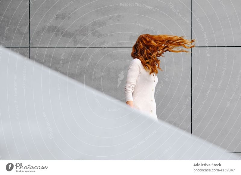 Ginger Frau mit fliegenden Haaren stehen in der Nähe der Wand Rotschopf Ingwer Behaarung Wind urban Stil lange Haare modern fliegendes Haar rote Haare trendy