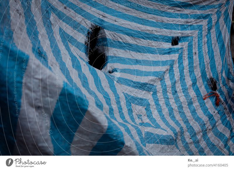 Blau-weiß gestreifte Zeltplane mit großen Löchern dient als Sicht- und Wetterschutz Inspiration Menschenleer Farbfoto Verfügbares Licht Außenaufnahme
