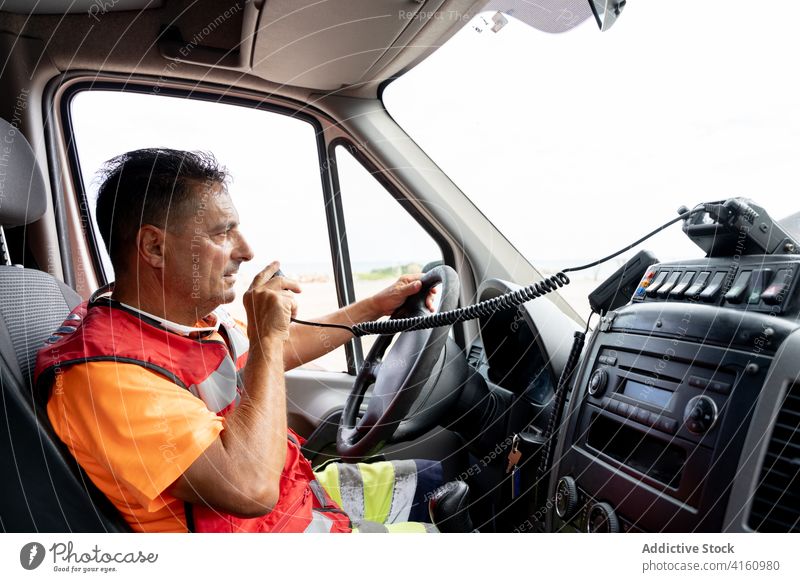 Mitarbeiter eines Krankenwagens, der das Fahrzeug fährt, während er mit einem Funkgerät spricht Fahrer reden Walkie-Talkie Laufwerk Arbeit Kommunizieren Uniform