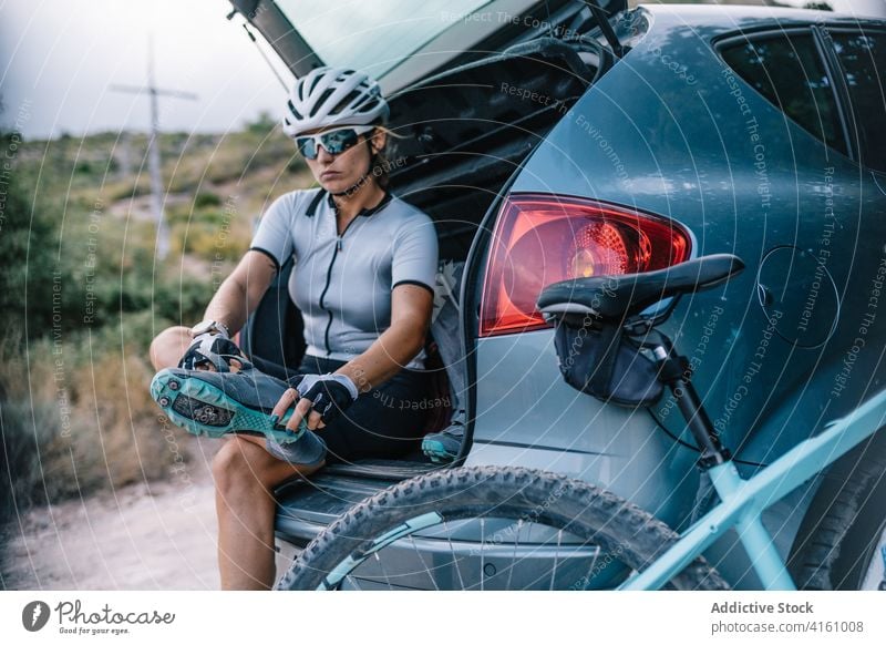 Entschlossene Radfahrerin bereitet sich auf die Fahrt vor Schutzhelm Kofferraum PKW Frau vorbereiten Fahrrad Reiter professionell Bestimmen Sie Sonnenbrille