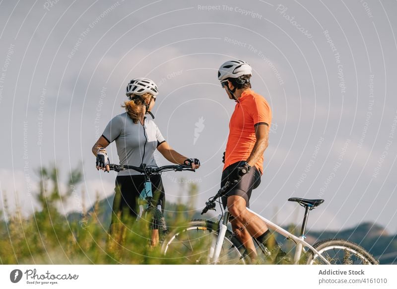Fröhliche Radfahrer stehen auf einem Hügel in den Bergen Paar Zusammensein Berge u. Gebirge Sport Schutzhelm professionell Fahrrad sich[Akk] entspannen Pause