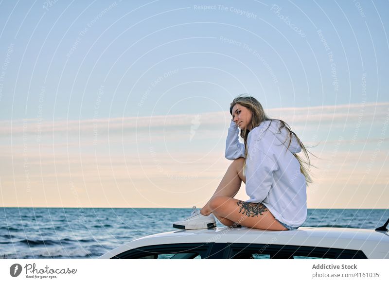 Entspannte Frau auf dem Dach eines Autos am Meer PKW Reisender sich[Akk] entspannen Seeküste Urlaub Fernweh Abenteuer Sonnenuntergang Abend MEER Sommer Natur