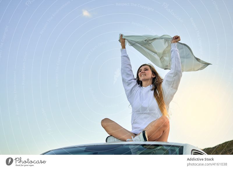 Ruhige Frau auf Autodach mit flatterndem Tuch Wind Stoff Reisender Freiheit sorgenfrei genießen PKW Dach Automobil Spielfigur sitzen reisen Abenteuer