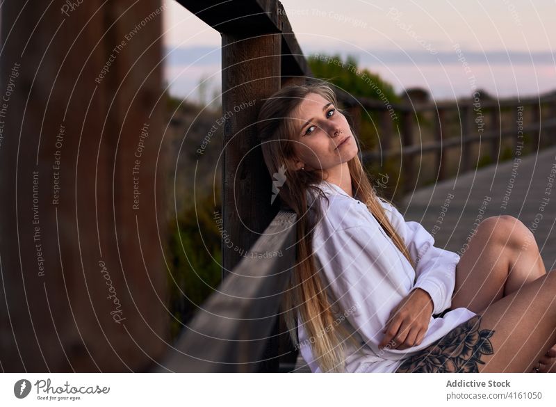 Friedliche Frau entspannt sich bei Sonnenuntergang auf der Promenade verträumt sich[Akk] entspannen Reisender sorgenfrei Windstille Spazierweg Abend Stauanlage