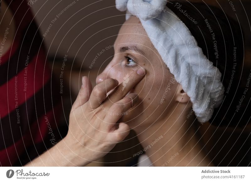 Visagist trägt Concealer auf das untere Augenlid einer Kundin auf Make-up Künstler bewerben Gesicht Kosmetik visagiste Hand Abdeckstift Stylist professionell