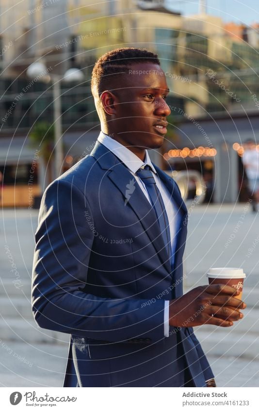Eleganter schwarzer Geschäftsmann mit Kaffee zum Mitnehmen auf der Straße Imbissbude trinken urban formal modern Tasse Exekutive elegant Anzug Manager