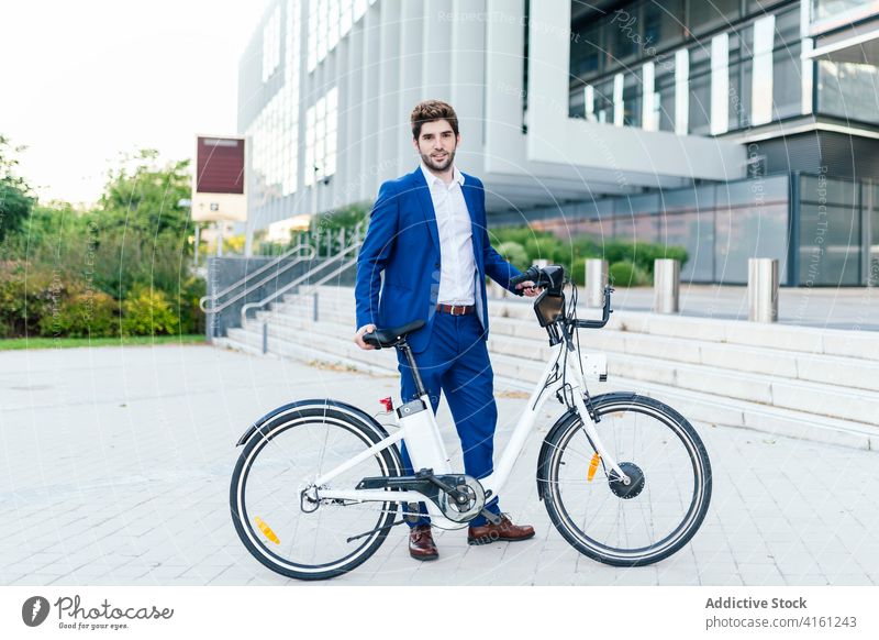Stilvoller Mann im Anzug zu Fuß auf dem Bürgersteig mit Elektrofahrrad stylisch Bekleidung Mode elektrisch Fahrrad Spaziergang Arbeitsweg Straße maskulin formal