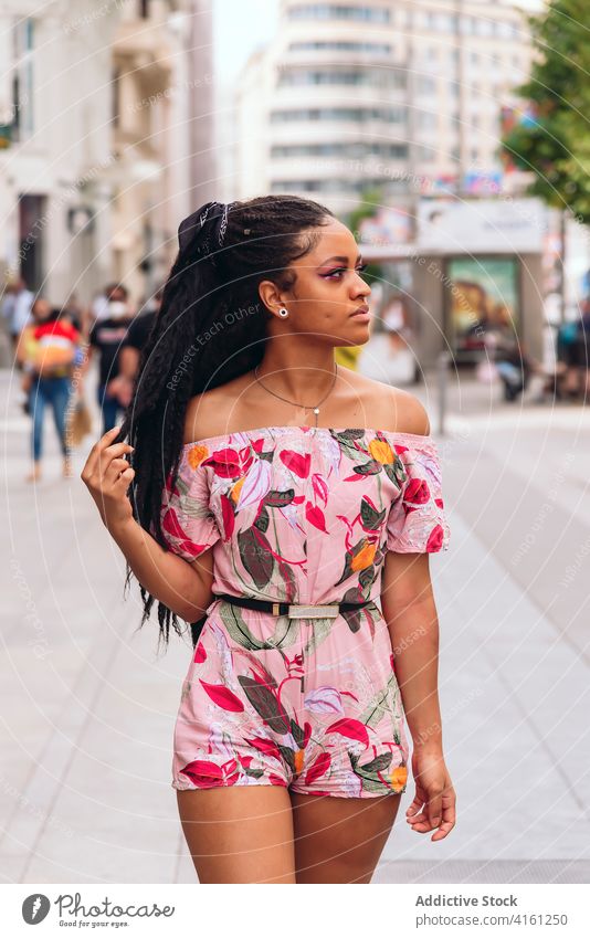 Ethnische Frau in trendiger Kleidung auf dem Straßenpflaster stylisch Outfit freundlich schwarz Afrikanisch Amerikaner Ornament genießen offen Straßenbelag