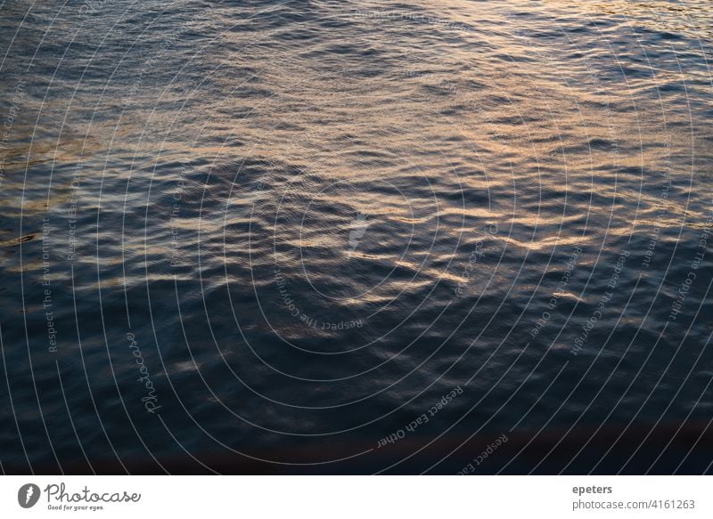 Dunkle, ruhige Wasseroberfläche während des Sonnenuntergangs Oberfläche Wellen Meer blau Menschenleer Sonnenlicht Außenaufnahme Natur Abend Sonnenaufgang