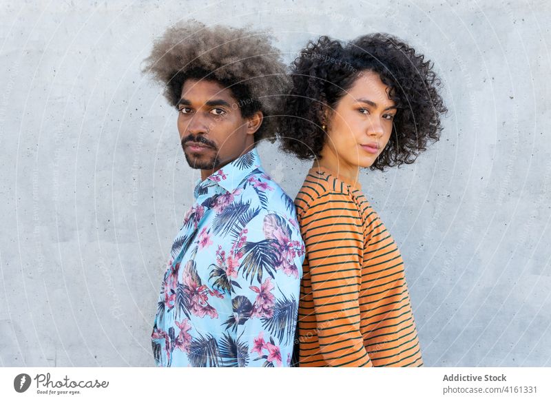 Multiethnische Freunde in stilvoller Kleidung in der Nähe einer Zementmauer Paar stylisch Bekleidung Frisur Afro-Look achtsam Freundschaft Wand Porträt