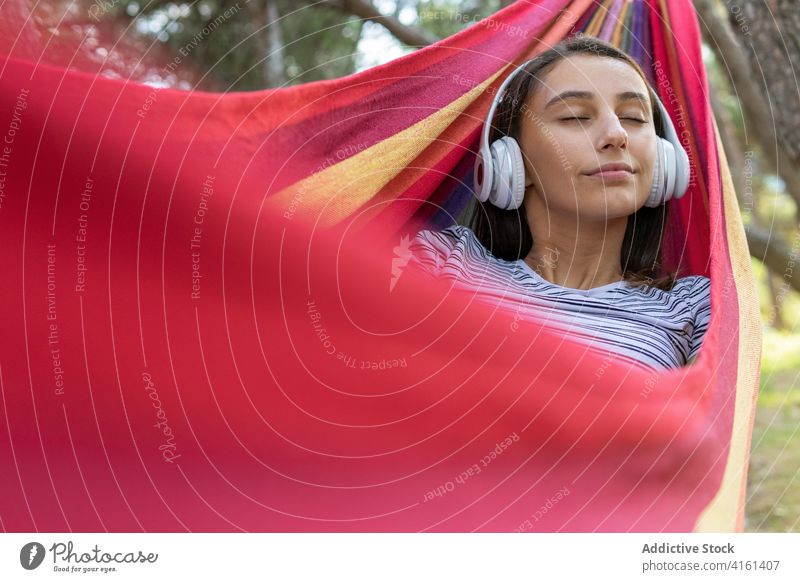 Sorglose Frau hört Musik in der Hängematte zuhören genießen hängen Park Drahtlos Melodie Windstille Kopfhörer friedlich Klang Lügen Gelassenheit Gesang Harmonie