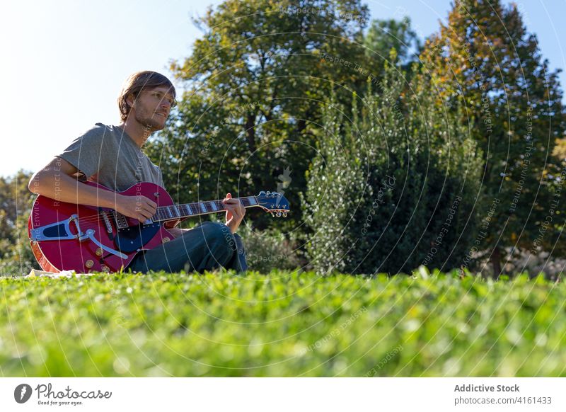 Mann spielt Gitarre im Park spielen elektrisch Musik Musiker Instrument Melodie Sommer männlich sonnig unterhalten Gras Hobby heiter ruhen Glück üben Rasen