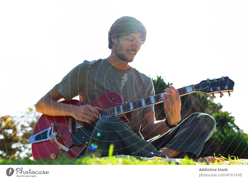 Mann spielt Gitarre im Park spielen elektrisch Musik Musiker Instrument Melodie Sommer männlich sonnig unterhalten Gras Hobby heiter ruhen Glück üben Rasen