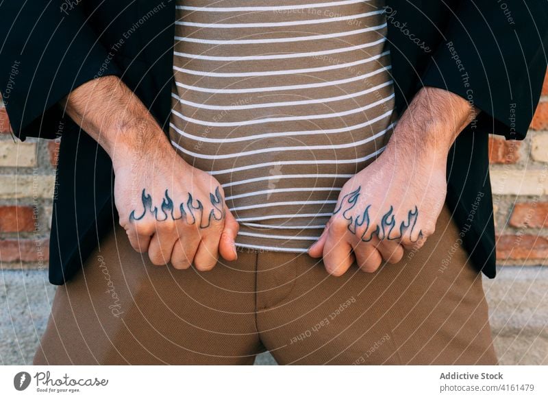 Gesichtsloser Mann mit ornamentaler Tätowierung an den Händen zeigen Tattoo Stil Ornament kreativ Design modern Straße Stadt stylisch Bekleidung Backsteinwand