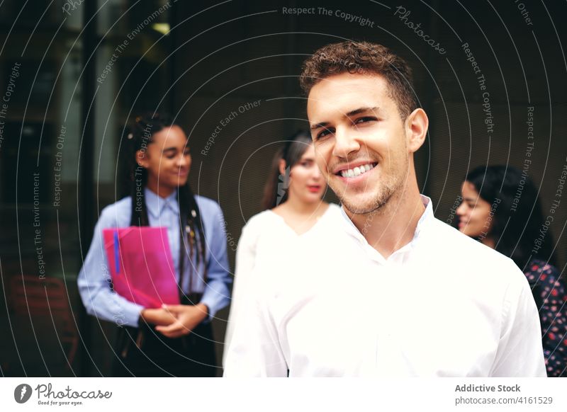 Positive Schülerin vor multiethnischen Kollegen auf der Straße Lächeln herzlich Geflecht Mappe angenehm freundlich Mitarbeiterin reden Mann stylisch Bekleidung
