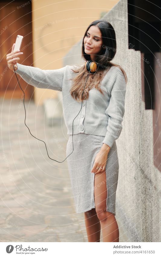 Charmante Frau mit Smartphone und Kopfhörer auf der Straße unter Selfie Musik Stil verbinden ruhig lässig ruhen Melodie zuhören Großstadt urban Audio