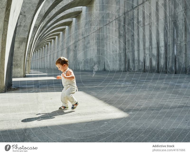Fröhliches Kleinkind, das unter einer gewölbten Konstruktion läuft Spaziergang heiter Kind Großstadt niedlich Freude Lächeln neugierig Weg bezaubernd Bogen