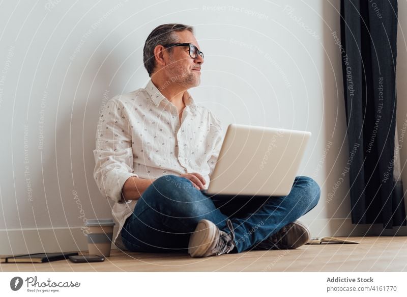 Nachdenklicher Mann arbeitet am Laptop auf dem Boden besinnlich Arbeitsplatz klug nachdenken Netbook benutzend Gerät Fokus positiv Apparatur Konzentration Stock