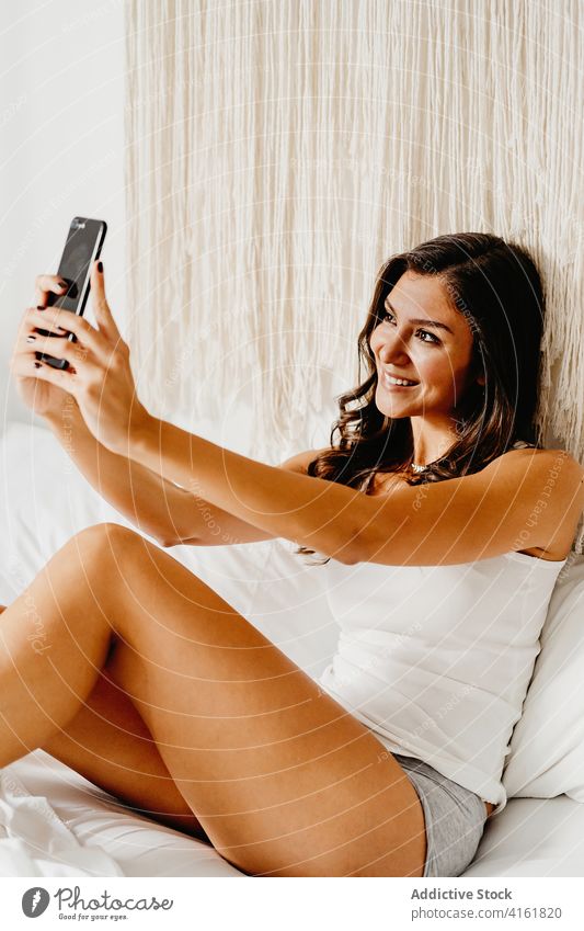 Positive junge Frau nimmt Selfie im Schlafzimmer Bett Morgen heimwärts heiter Smartphone Glück teilen Teenager tausendjährig Apparatur Gerät soziale Netzwerke