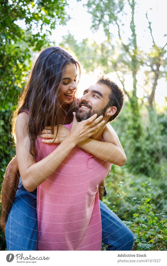 Verspieltes junges ethnisches Paar hat Spaß im Park Glück Liebe Partnerschaft spielerisch Spaß haben Huckepack romantisch Gesicht berühren Lächeln Zuneigung