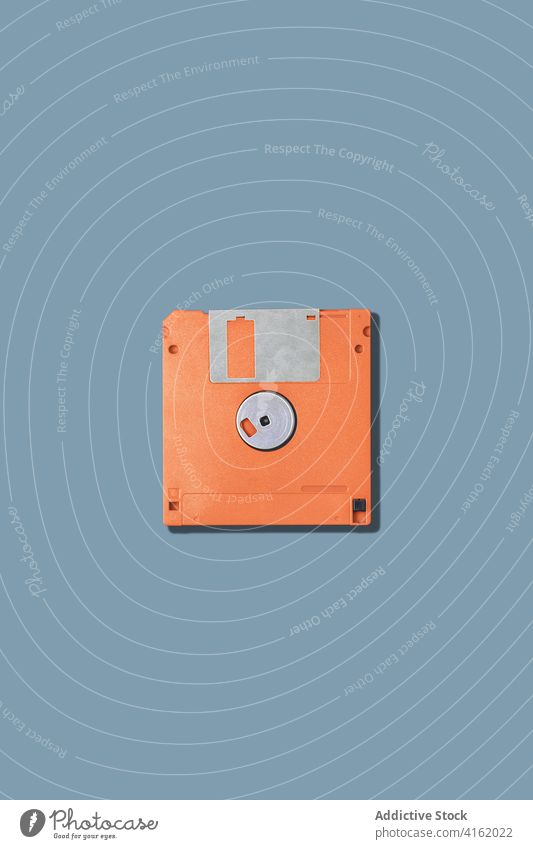 Computer-Diskette auf grauem Hintergrund Floppy Lamelle alt pc altmodisch Information Daten veraltet orange Gerät Werkzeug altehrwürdig retro Accessoire