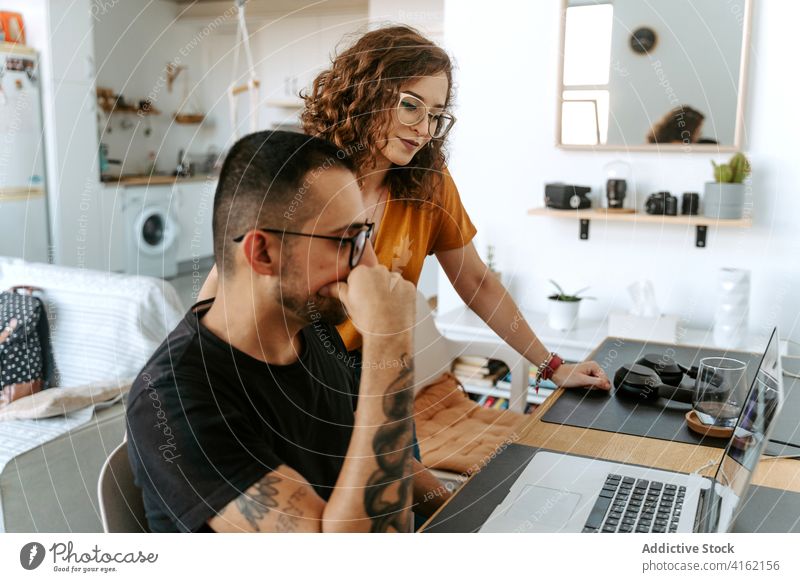 Konzentriertes junges gemischtes Paar arbeitet zu Hause am Laptop Arbeit abgelegen heimwärts abstützen Teamwork freiberuflich Konzentration benutzend Gerät