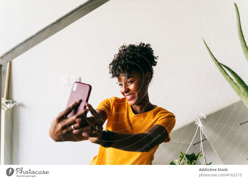 Lachende schwarze Frau nimmt Selfie mit Smartphone zu Hause benutzend heimwärts Spaß haben aufgeregt Browsen Mobile heiter tausendjährig jung Jugendlicher