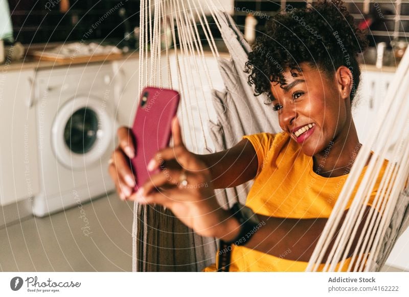 Ethnische junge Frau nimmt Selfie zu Hause heimwärts Smartphone heiter teilen Mobile Telefon Lächeln sorgenfrei positiv Schüler Afroamerikaner schwarz ethnisch