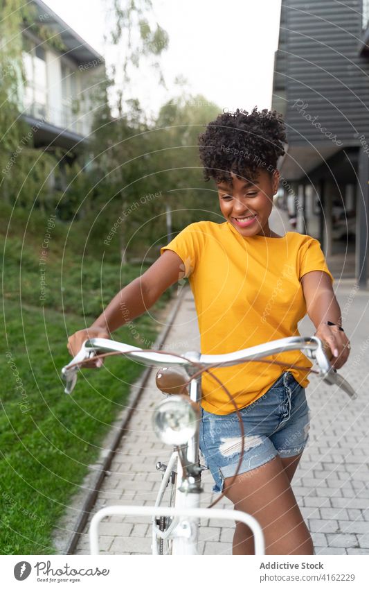 Positive schwarze Frau fährt Fahrrad auf der Straße Mitfahrgelegenheit Glück Aktivität Sommer urban trendy positiv jung Afroamerikaner ethnisch tausendjährig