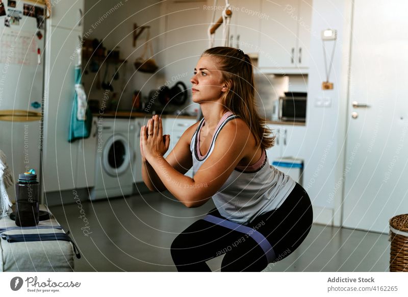 Konzentrierte Sportlerin bei Kniebeugen mit Gummiband in der Wohnung Bestimmen Sie Konzentration Übung Widerstandsband Fokus Motivation Fitness Training