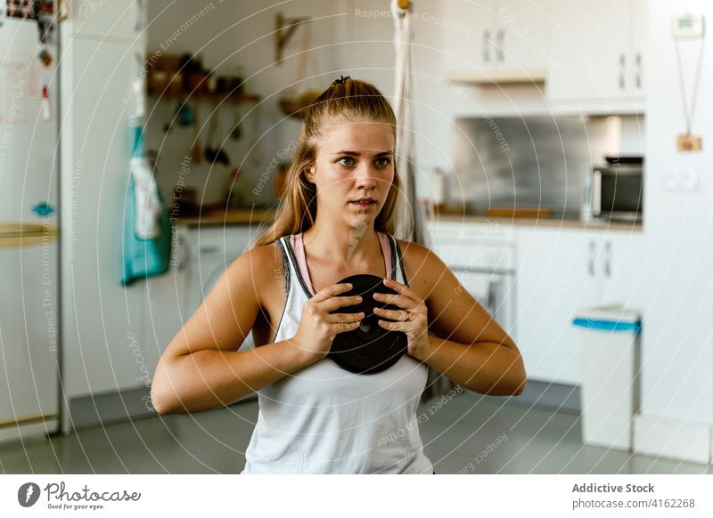Konzentrierte junge Sportlerin bei Übungen mit Gewichten zu Hause Frau Training Teller Konzentration Bestimmen Sie Energie Wohlbefinden Vitalität Wellness