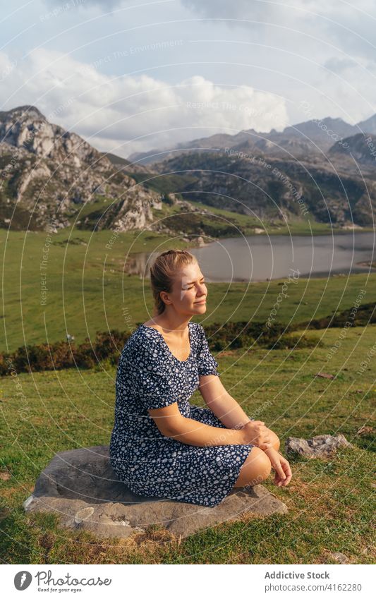 Auf einem Stein ruhende Frau vor einem spektakulären Bergtal Hochland Berge u. Gebirge prunkvoll bewundern Gelände Teich Landschaft Ambitus See Hügelseite Natur