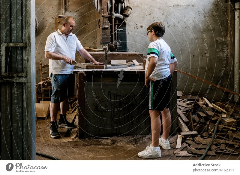 Männlicher Holzarbeiter bringt seinem Sohn das Sägen von Holz bei Tischlerin Werkstatt Vater lehren lernen Zimmerer Schreinerei Holzarbeiten geschnitten hölzern