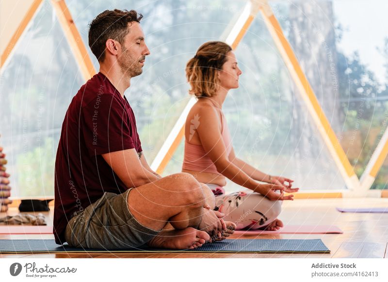 Paar sitzt in Lotus-Pose beim Meditieren auf der Yogamatte meditieren Beine gekreuzt Augen geschlossen Zen Sprit Energie Achtsamkeit Klasse Barfuß passen