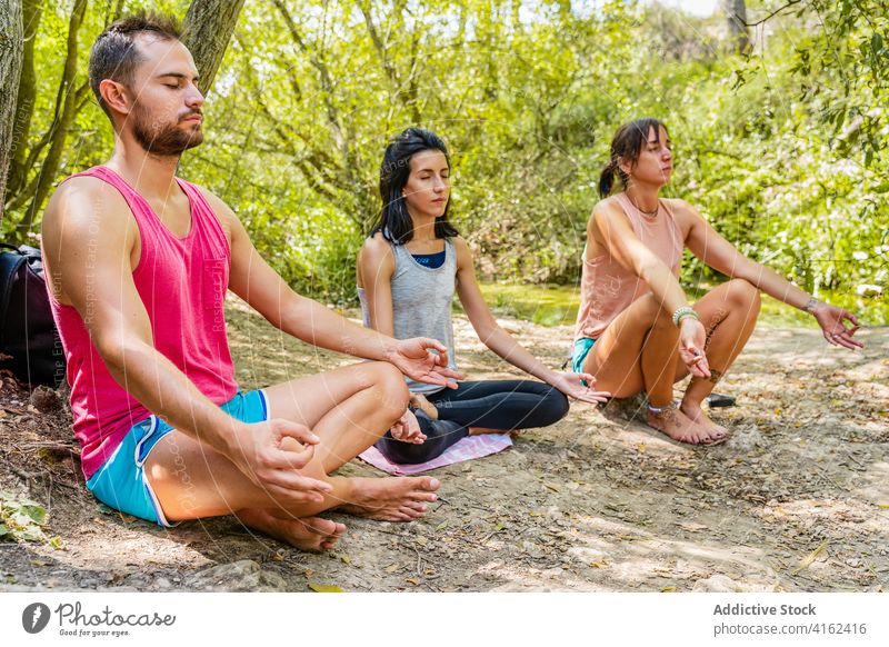 Menschen sitzen in Padmasana Pose auf Gehweg in der Nähe von Bäumen padmasana Yoga meditieren reflektierend Augen geschlossen Sprit Beine gekreuzt Zen Weg