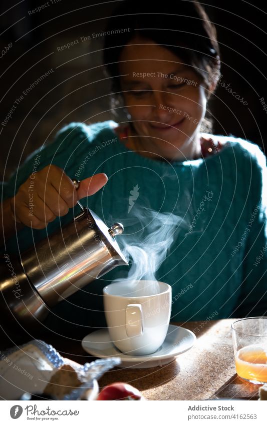 Lächelnde Frau beim Frühstück zu Hause Kaffee Morgen heimwärts eingießen Geysir Kaffeemaschine aromatisch trinken heiß Heißgetränk Getränk Aroma Becher Koffein