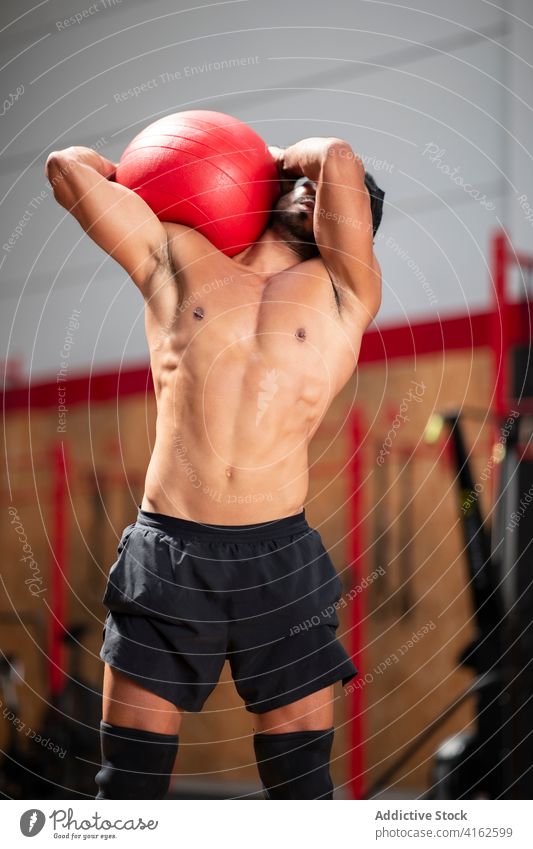 Entschlossener ethnischer Sportler mit Fitnessball beim Training im Fitnessstudio Athlet Ball Muskel Bestimmen Sie Fokus Übung Mann operativ muskulös stark