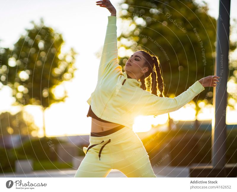 Aktive junge ethnische Dame tanzt bei Sonnenuntergang im Park Frau Tanzen ausführen aktiv Bewegung trendy Anmut traumhaft Energie modern Ballerina Sonnenlicht