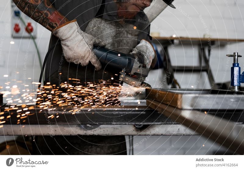 Männlicher Arbeiter mit elektrischer Schleifmaschine in der Werkstatt Maschine Mann geschnitten Schweißer Metallbearbeitung Funken männlich Detailaufnahme