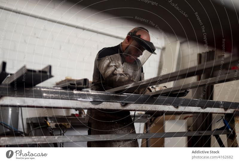 Fokussierter Schweißer in Schürze in der Werkstatt Mann Schweißnaht dreckig Grunge Detailaufnahme Metallbearbeitung Arbeiter männlich ernst Industrie Werkzeug