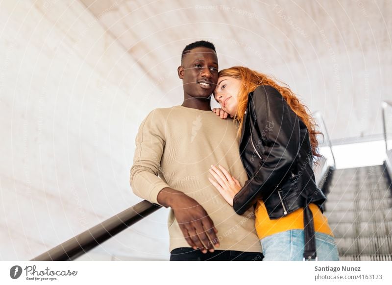 Liebevolles multiethnisches Paar-Portrait Treppe Lächeln umarmend die sich gegenseitig ansehen Porträt Vorderansicht Stehen Partnerschaft multirassisch