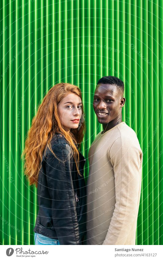 Multiethnisches Paar-Portrait grüner Hintergrund Porträt in die Kamera schauen Lächeln Vorderansicht Partnerschaft multirassisch Schwarzer Mann Kaukasier