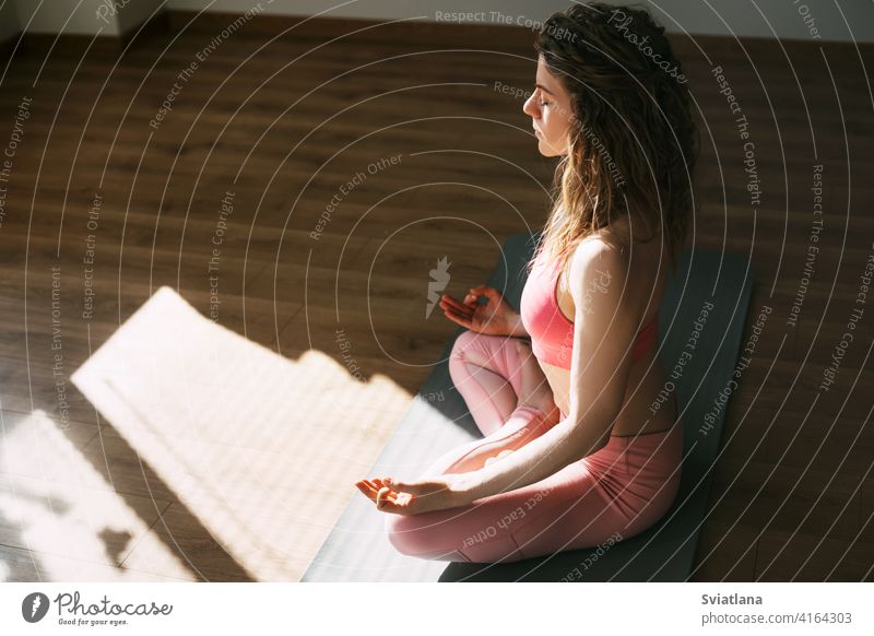 Ein junges Mädchen mit geschlossenen Augen meditiert im Lotussitz im Klassenzimmer.Sport, Fitness, Yoga. Seitenansicht, Platz für Text Frau Lotos meditierend