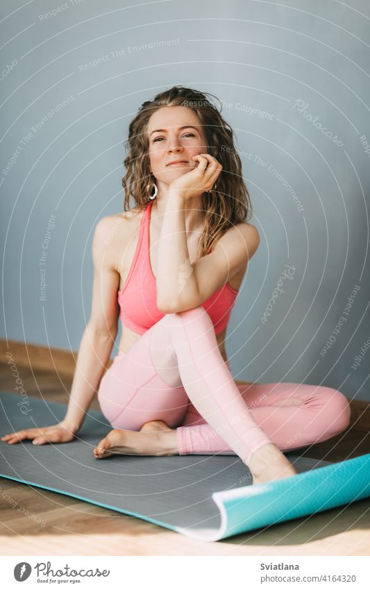 Eine junge Frau sitzt auf einer Yoga-Matte und ruht sich nach einem Training aus. Sport, Fitness. Gesunder Lebensstil Konzept Unterlage Sitzen schön Mädchen